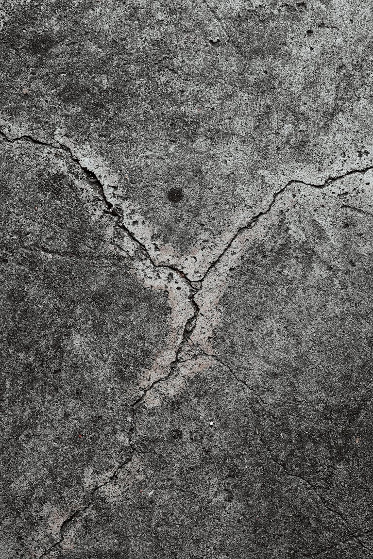 Close-up of cracked concrete surface showing texture and cracks, perfect for backgrounds.